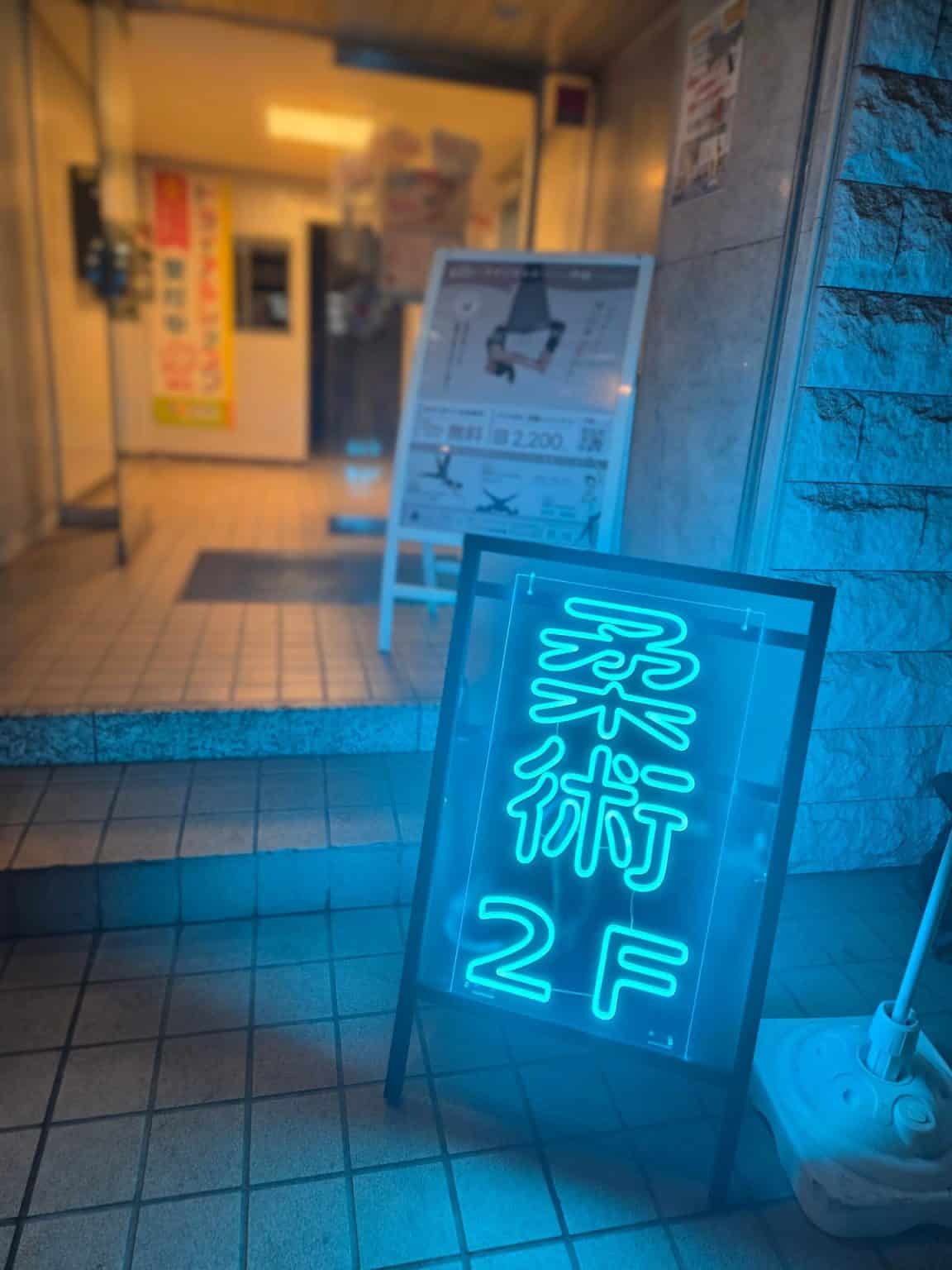 ビル入口に置かれた「柔術 2F」のネオン看板